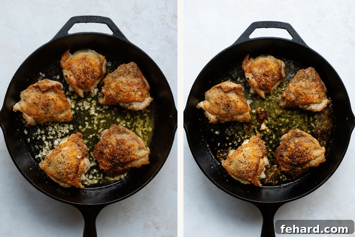 Overhead view of chicken thighs with crispy skin in a cast iron skillet, with butter and garlic infusing on the side.