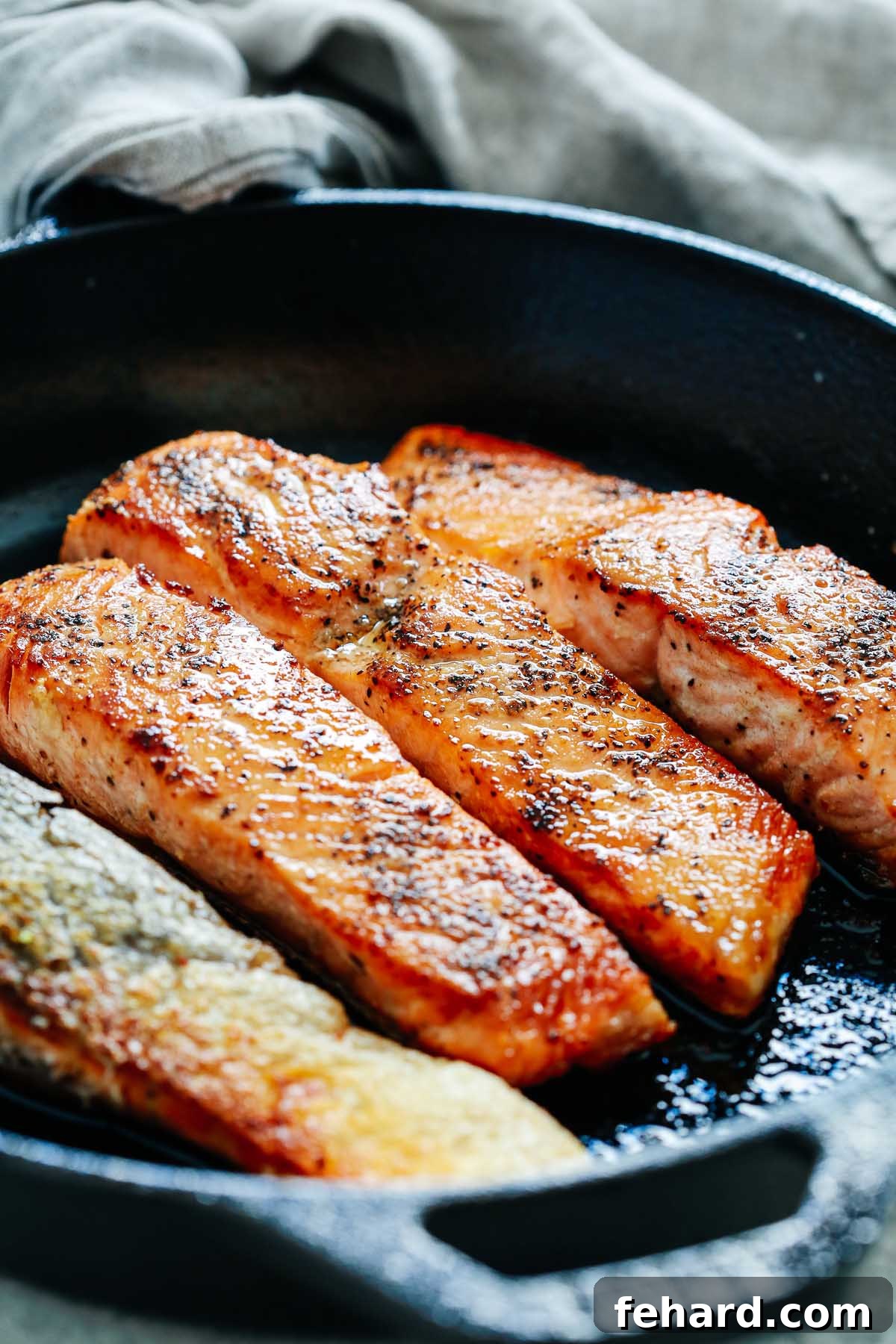Crispy Golden Pan Seared Salmon 2 Four perfectly pan-seared salmon fillets in a cast iron skillet, golden brown and ready to serve