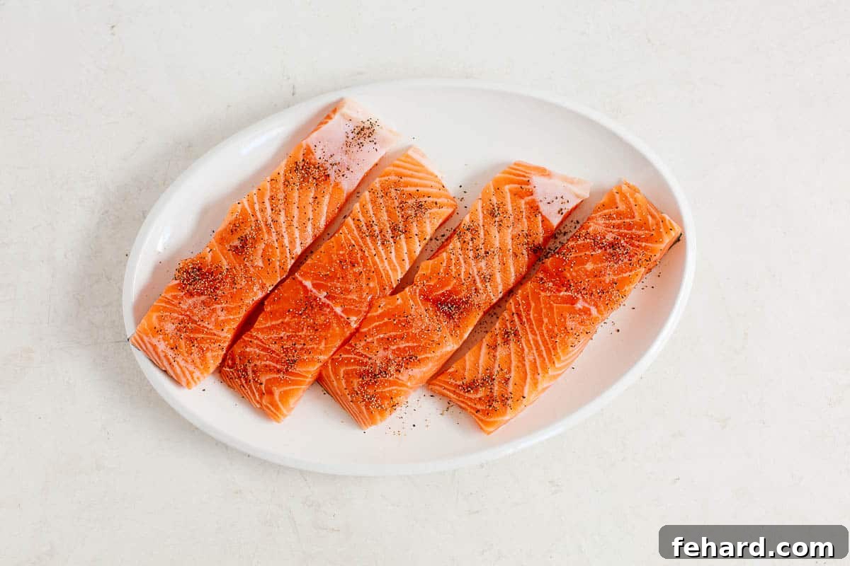 Crispy Golden Pan Seared Salmon 3 Four raw salmon fillets arranged neatly on a white platter, perfectly portioned for a meal