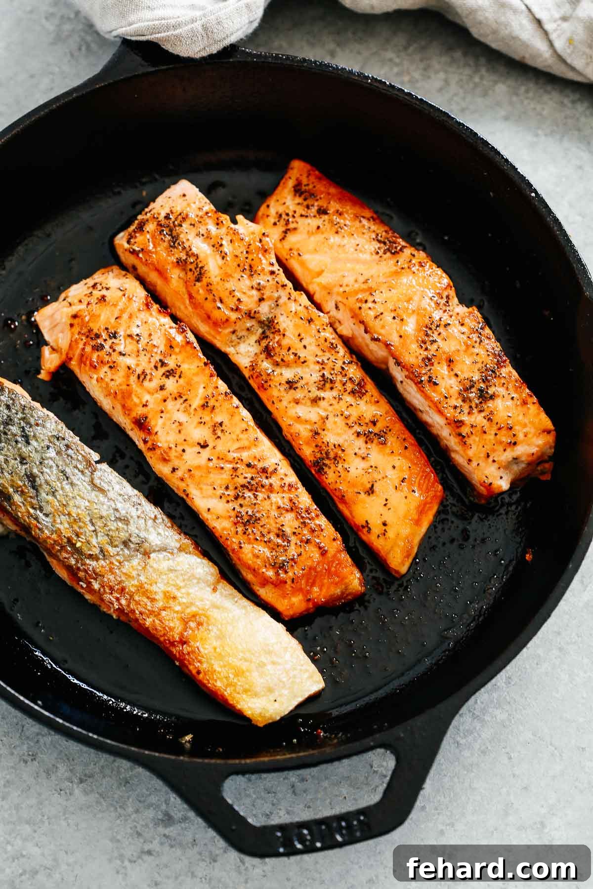 Crispy Golden Pan Seared Salmon 6 Four pieces of perfectly cooked pan-seared salmon resting in a black cast iron skillet