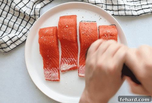 Close-up of a raw salmon fillet on a white plate, seasoned and ready for cooking