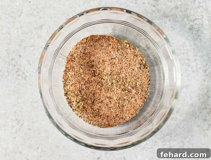 A small white bowl filled with a vibrant mixture of red and brown spices, representing the homemade blackening seasoning blend.