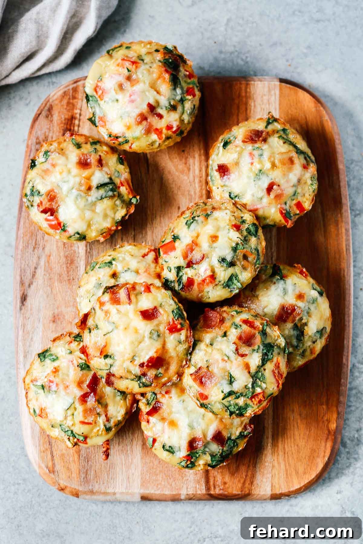 Close-up overhead photo of a wooden serving board laden with freshly baked breakfast egg muffins.