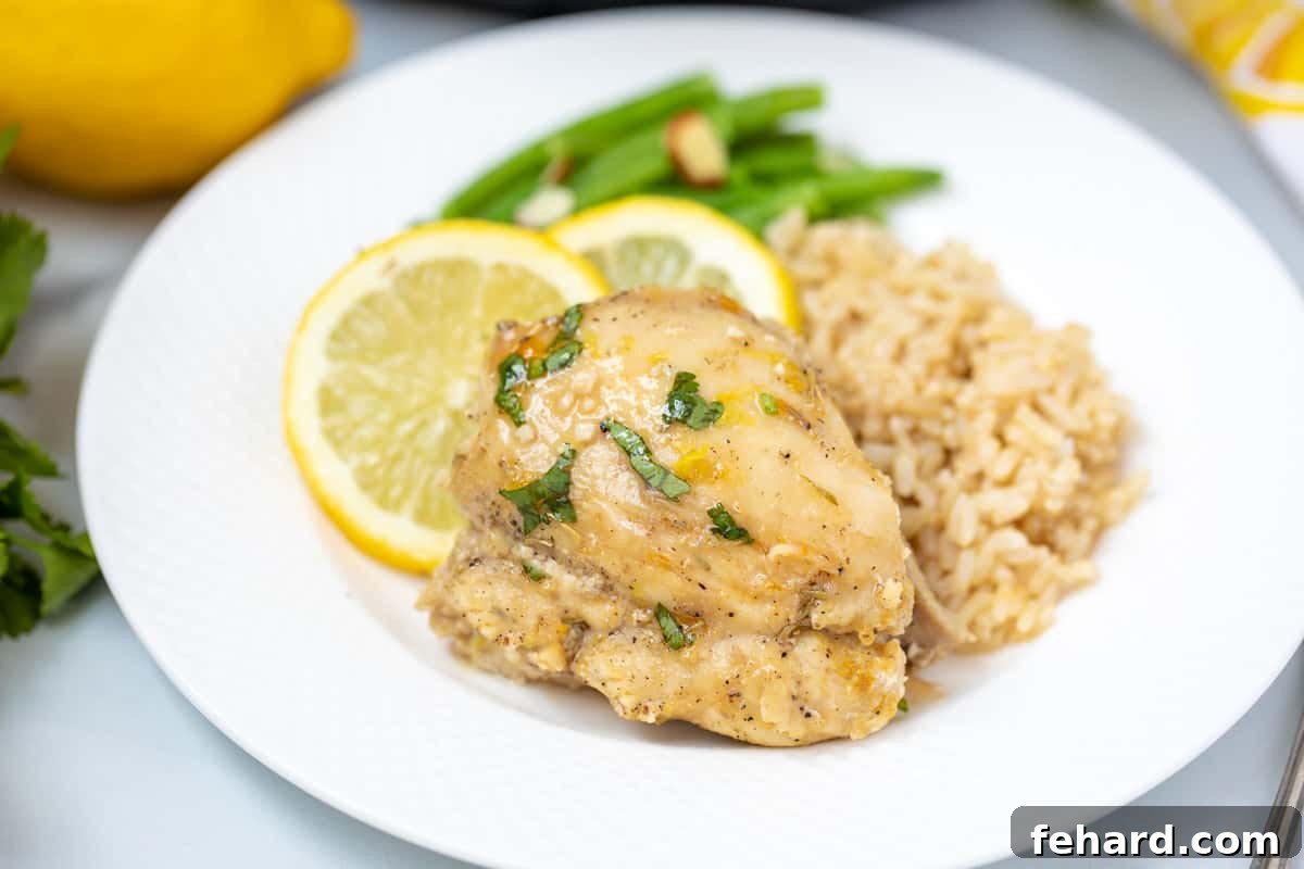 Instant Pot Lemon Chicken Thigh on a white plate next to brown rice. 