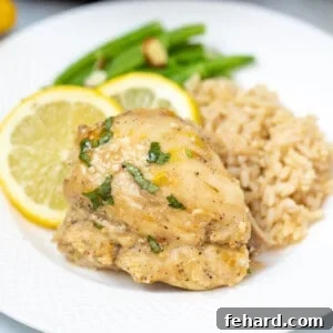Instant Pot Lemon Chicken Thigh on a white plate next to brown rice.