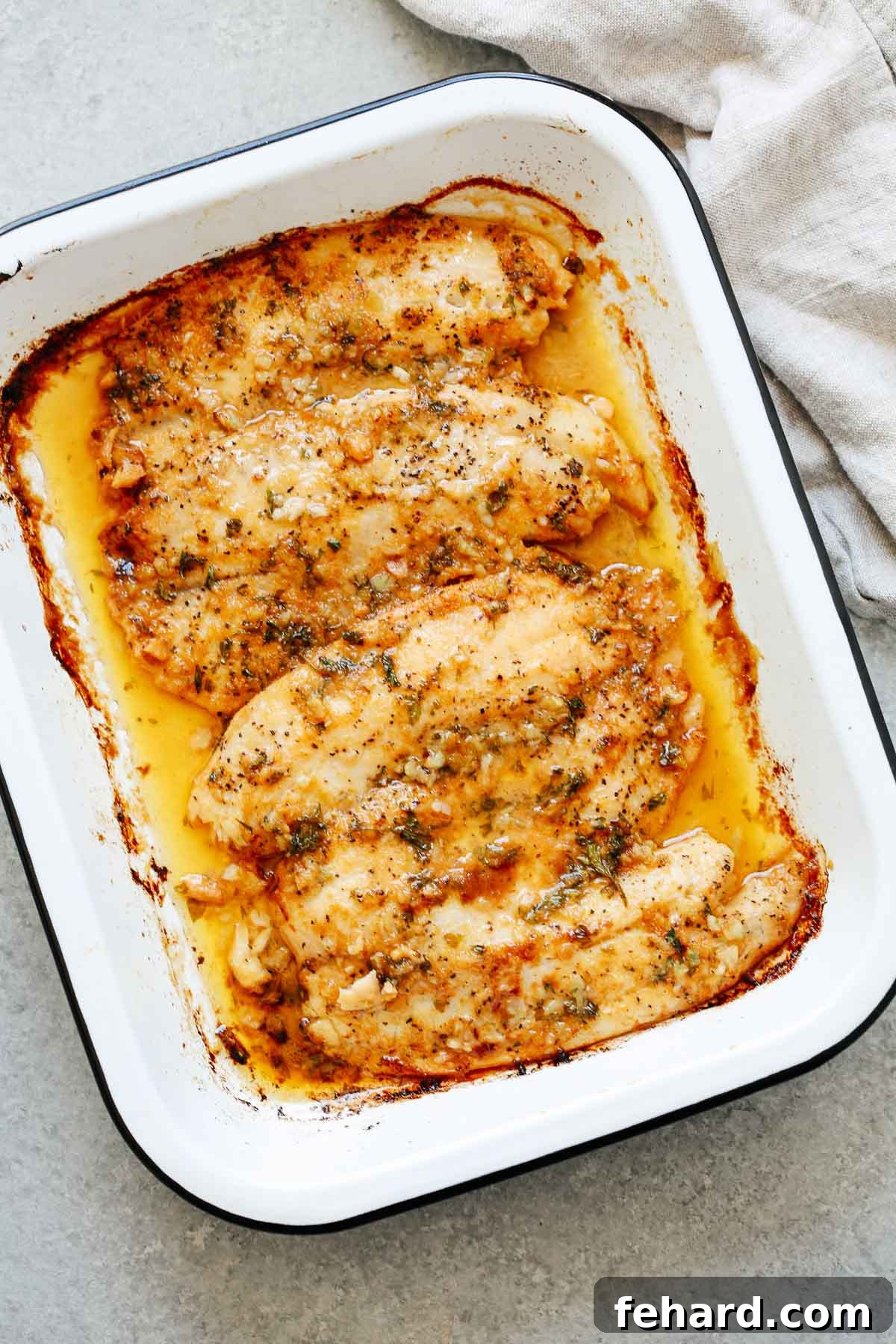 Perfectly cooked tilapia fillets with a rich garlic butter sauce in a white baking dish, ready to serve.