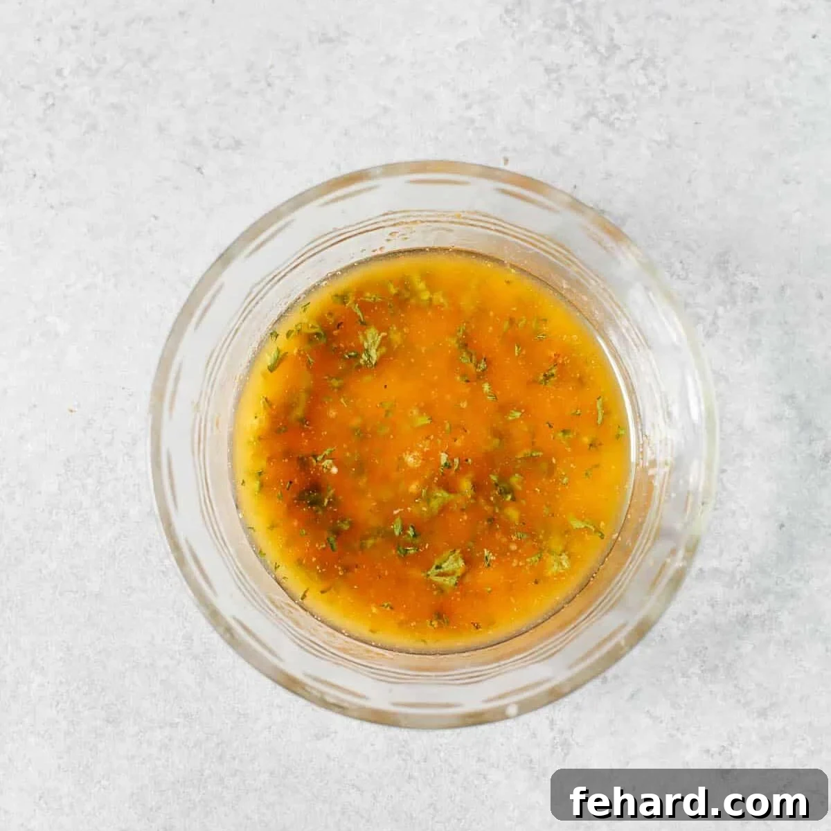 A glass bowl containing melted butter, minced garlic, lemon juice, and herbs for the sauce.