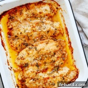 cooked tilapia fillets with garlic butter sauce in a white baking dish