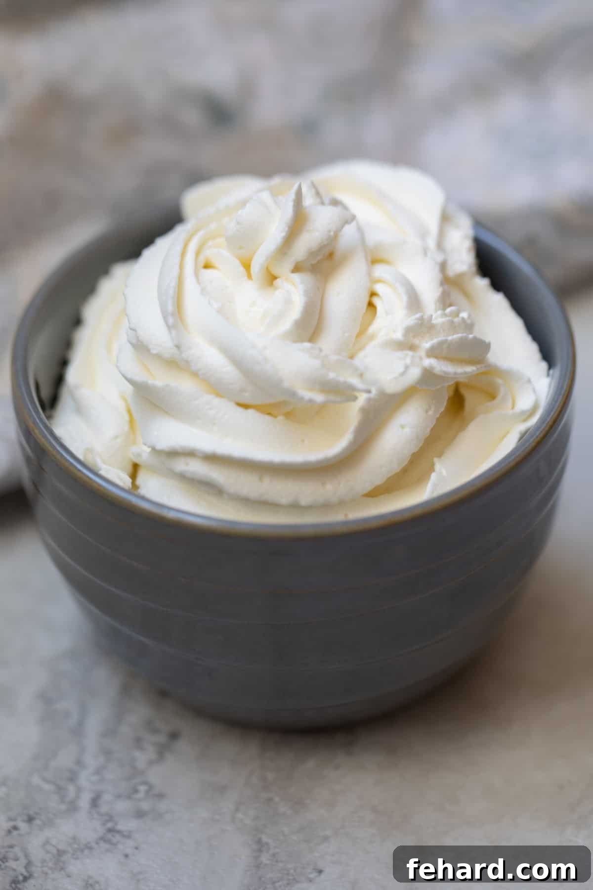 Bowl of freshly piped homemade whipped cream, showcasing its light and fluffy texture.