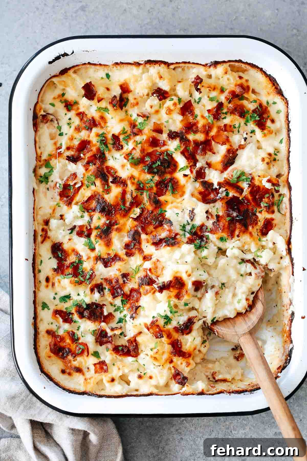 Golden Cauliflower Gratin 8 Close-up of a serving of cheesy cauliflower casserole scooped from a baking dish, highlighting the creamy texture and melted cheese.