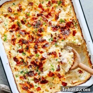 Golden Cauliflower Gratin 9 Close-up of a cauliflower casserole in a baking dish with a wooden spoon scooping a portion.