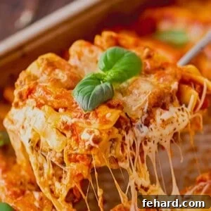 Slice of cheesy lasagna being pulled out of a baking dish, showcasing its perfect layers and golden-brown top.