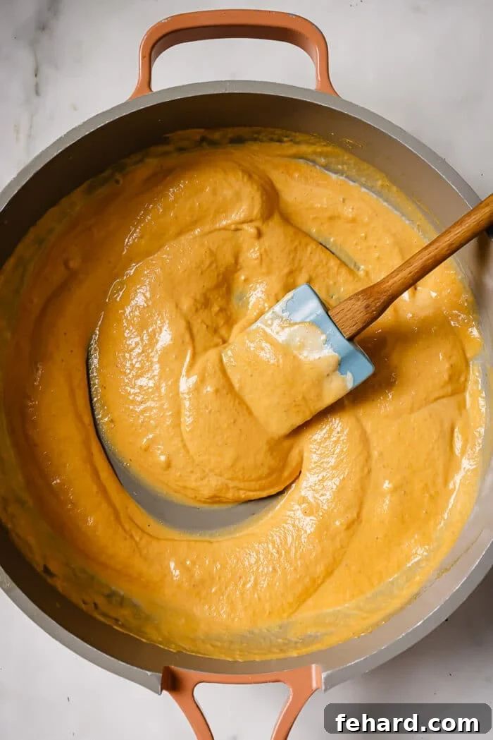 Pumpkin puree and heavy cream being added to the skillet with the infused butter, garlic, and sage.