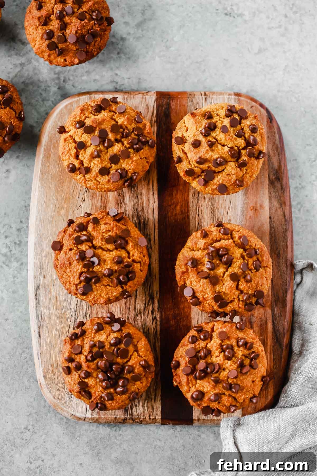 Six healthy pumpkin chocolate chip muffins artfully arranged on a rustic serving board, ready to be enjoyed.