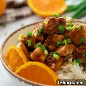 Bowl of orange chicken on top of rice.