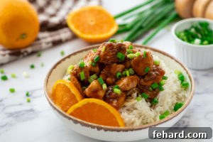 Bowl of Orange Chicken next to fresh oranges