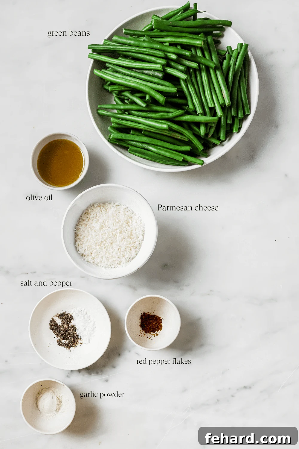 Garlic Parmesan Green Beans 3 Pre-measured ingredients for parmesan green beans laid out on a kitchen surface, including fresh green beans, olive oil, spices, and a block of Parmesan cheese.