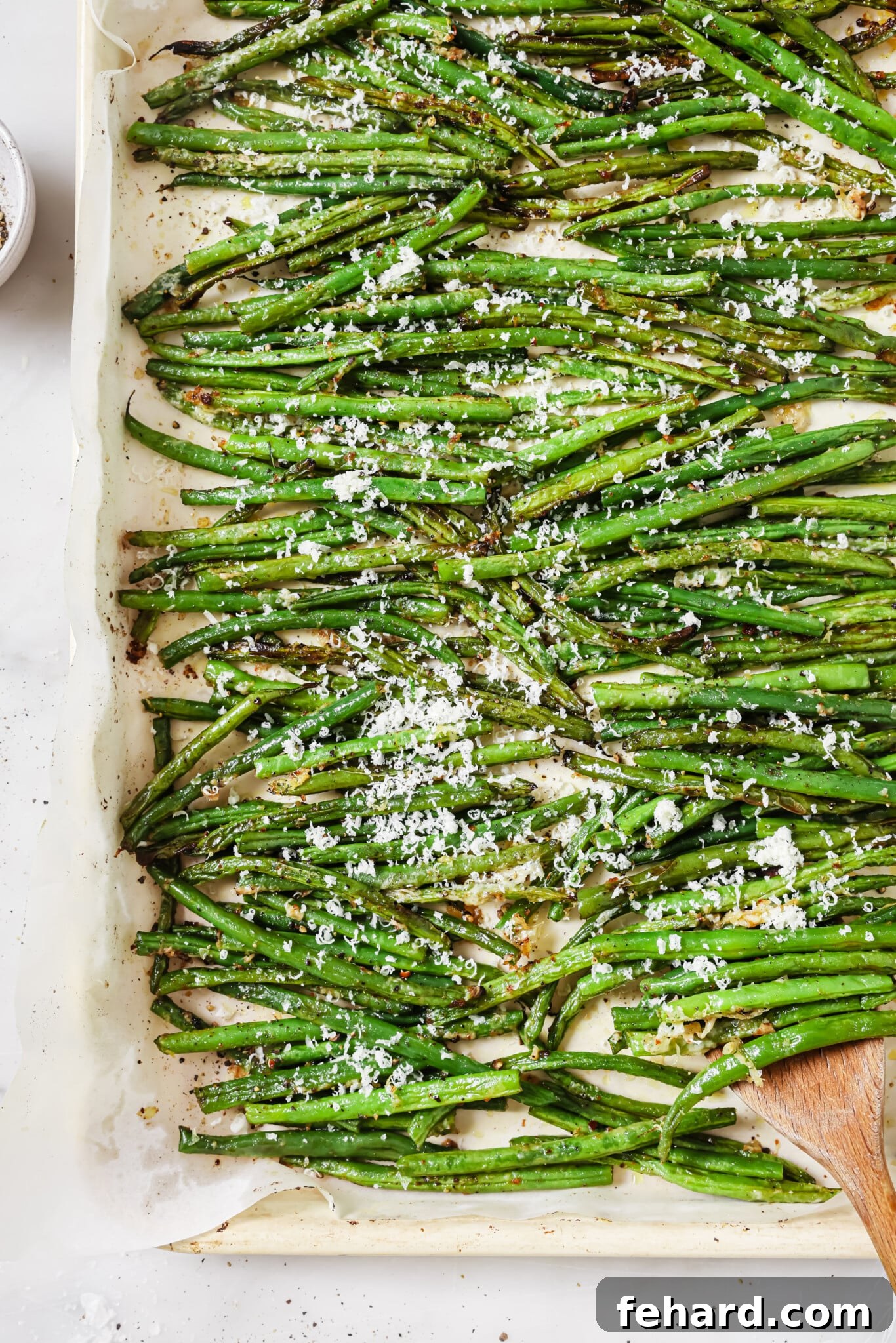 Garlic Parmesan Green Beans 7 Close up of a baking sheet of parmesan green beans, garnished with fresh herbs and ready to be served as a festive side dish.