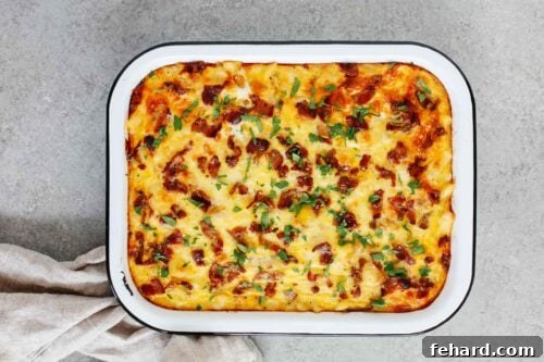 Overhead view of the fully baked Sausage and Potato Breakfast Casserole, beautifully golden and garnished with fresh green herbs.