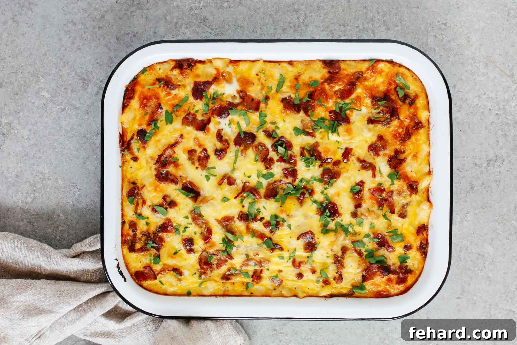 Overhead view of the fully baked Sausage and Potato Breakfast Casserole, beautifully golden and garnished with fresh green herbs like parsley.