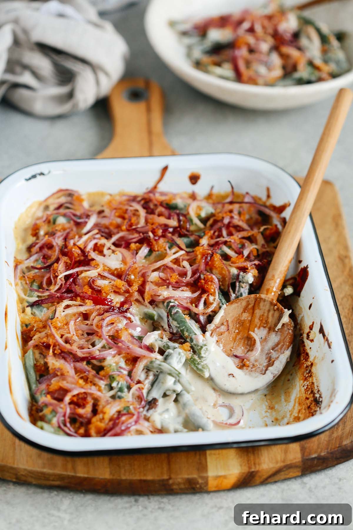 Angled image of Healthier Green Bean Casserole Recipe with a wooden spoon scooping a portion out. 