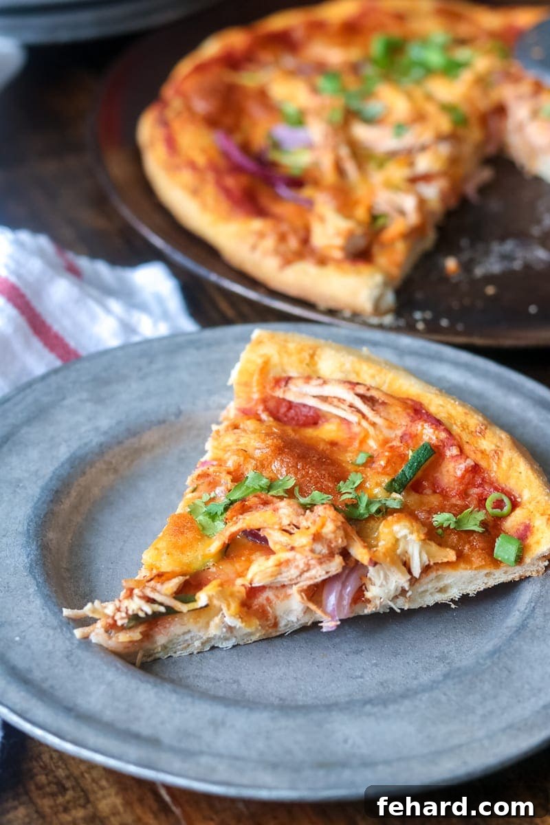 Creative Pizza Recipe using leftover chicken Slice of chicken fajita pizza on a silver plate, with the full pizza visible in the background.
