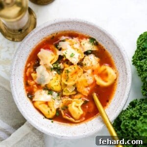 overhead view of tortellini soup in a white bowl.