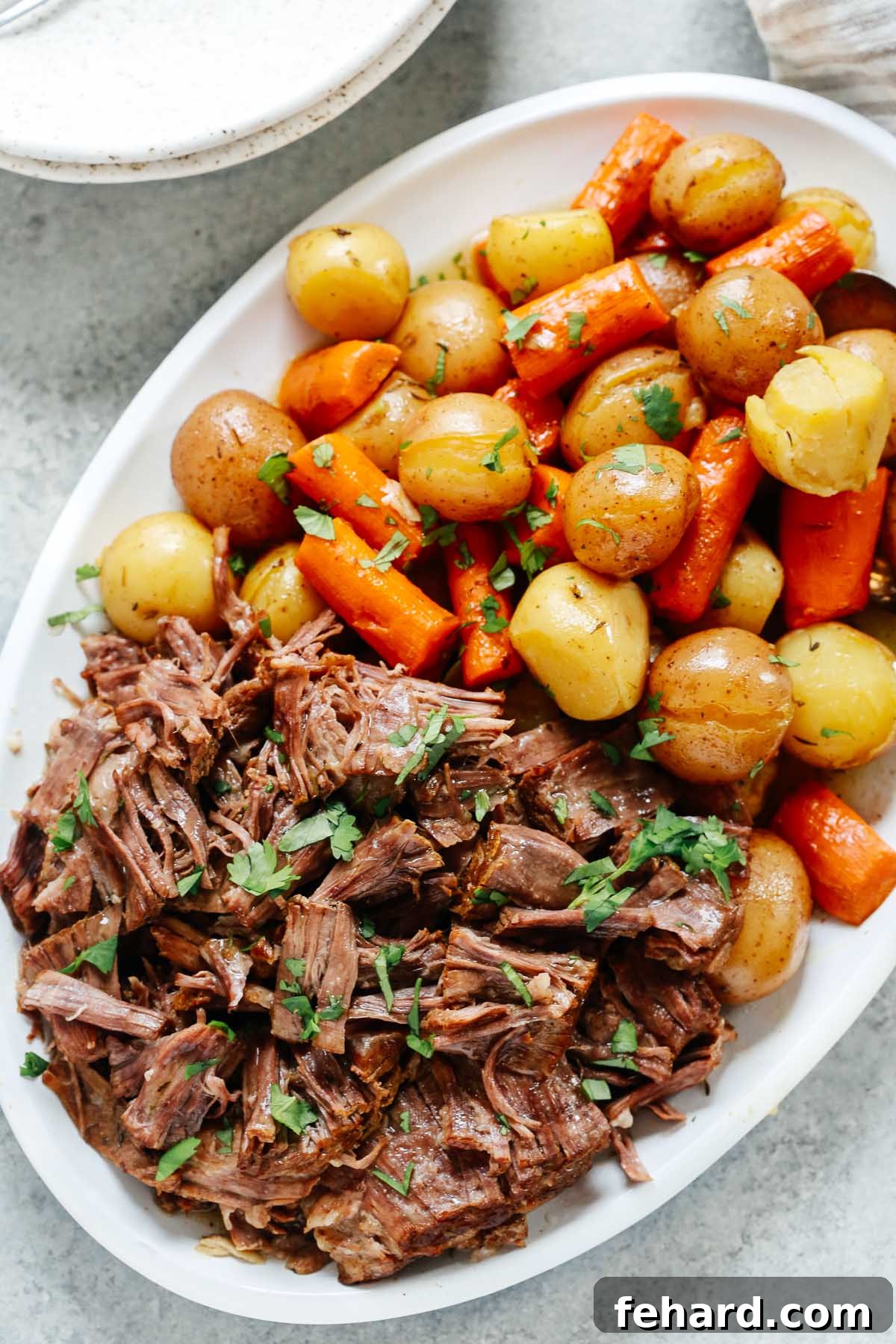 Ultimate Instant Pot Pot Roast 5 Pressure cooker pot roast recipe in a white serving plate with carrots and potatoes.