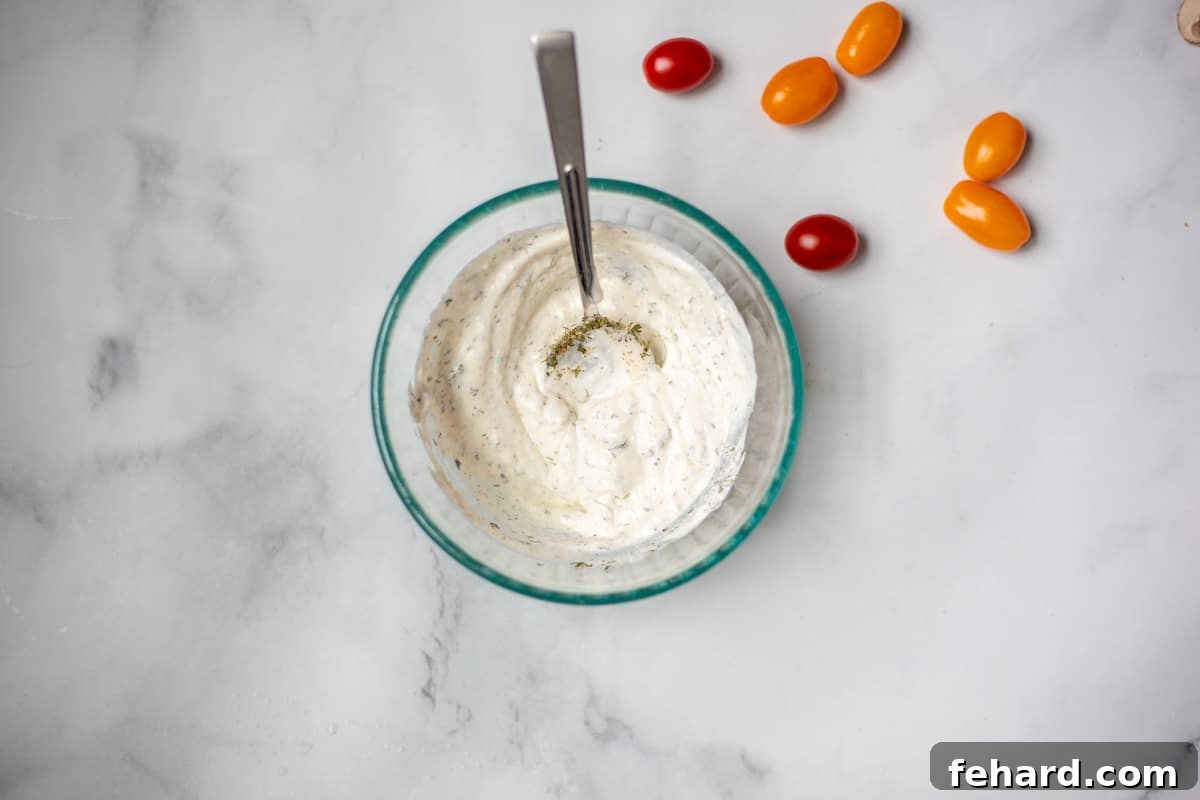 Glass bowl filled with creamy homemade buttermilk ranch dressing, being whisked to perfection.
