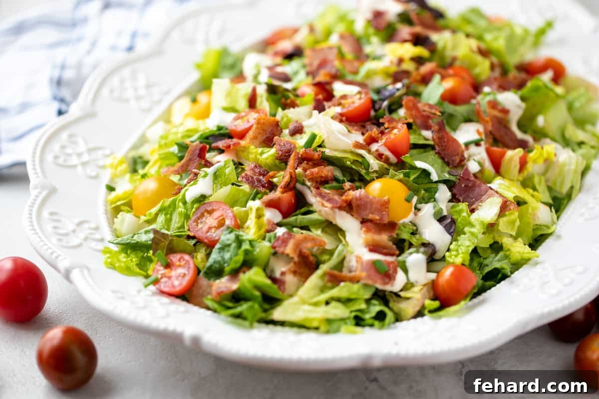 A large white platter presenting a beautifully assembled BLT Salad, generously drizzled with creamy ranch dressing, highlighting the fresh ingredients.