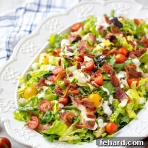 BLT Salad in white platter with next to cherry tomatoes and fresh chives.