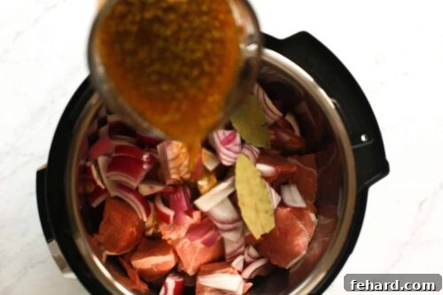 overhead view of beef broth being poured inside of an instant pot
