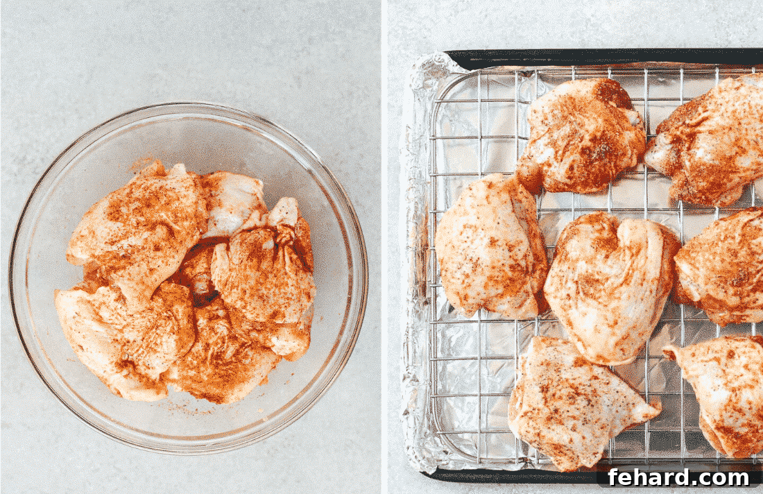 Raw chicken thighs coated with a vibrant paprika spice blend, arranged in a single layer on a wire rack set over a parchment-lined baking sheet, ready for baking.