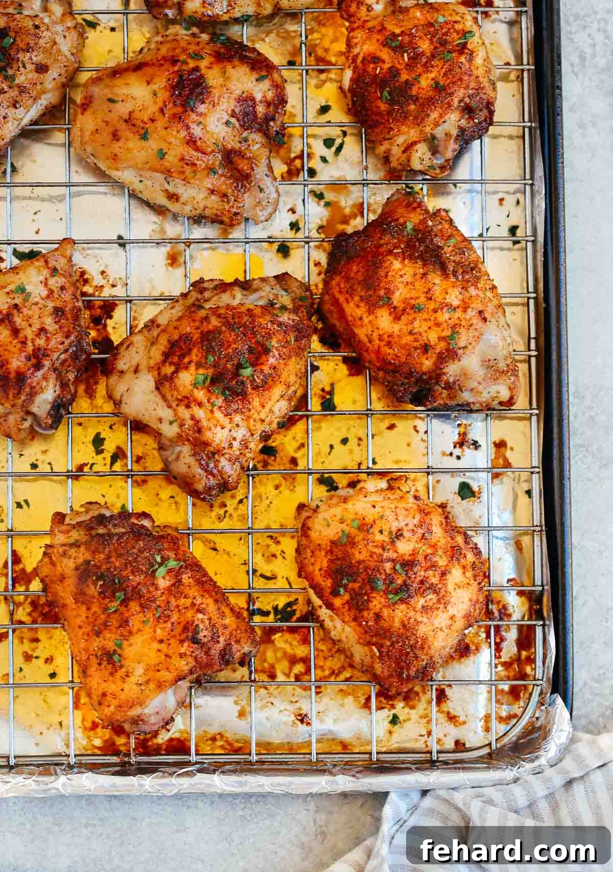 Freshly baked, golden-brown crispy chicken thighs cooling on a wire rack set over a sheet pan, steam gently rising, showcasing their juicy interior and perfectly seasoned skin.