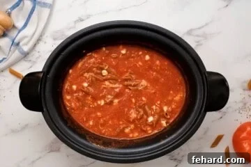 Cottage Cheese, pasta, and cheese mixed into spaghetti sauce inside a slow cooker.