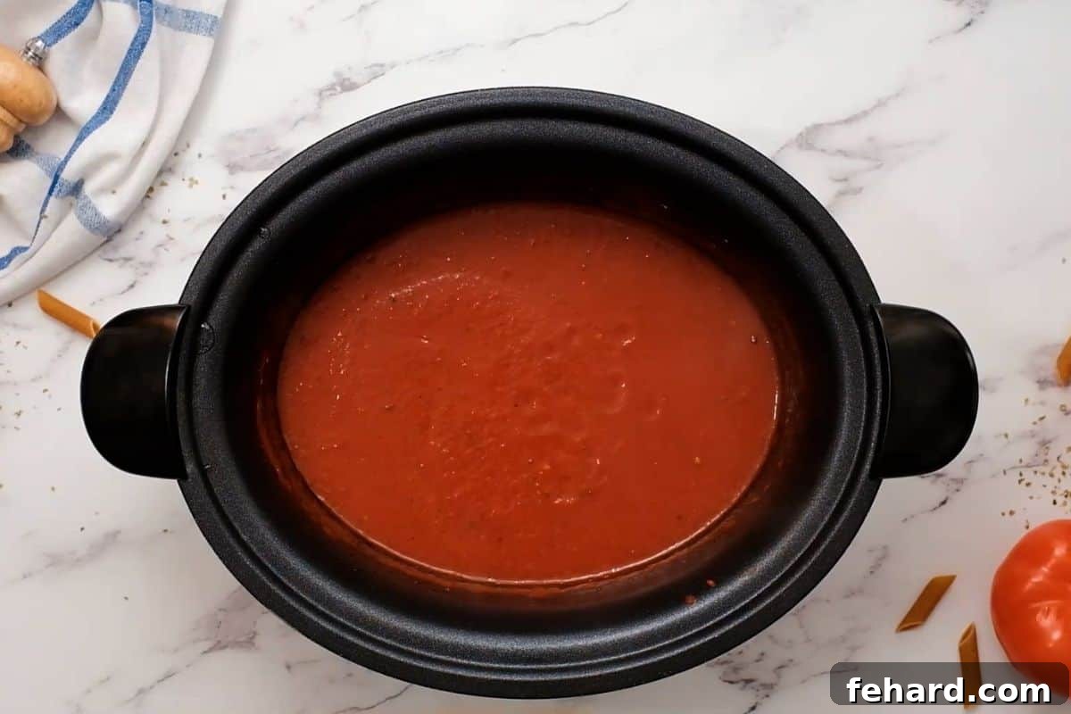 Slow Cooker Ziti Sauce Preparation Ingredients for homemade spaghetti sauce simmering in a crockpot before pasta is added.