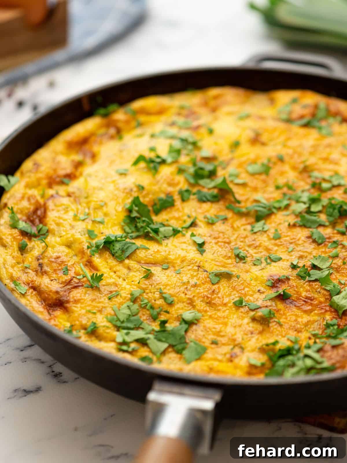 Baked frittata with potatoes and bacon in an oven-safe skillet, garnished with fresh herbs.