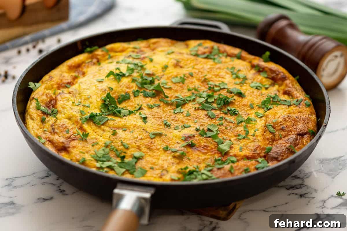 A perfectly baked potato and bacon frittata, golden brown and set, still in its oven-safe skillet.