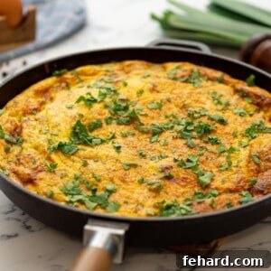 Baked potato frittata in skillet topped with fresh parsley.