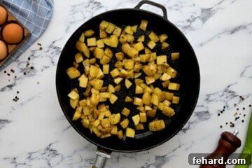 Sauteed potatoes in skillet seasoned with salt and pepper.