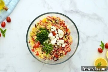 Bowl of cold couscous salad with added feta, mint, and parsley.