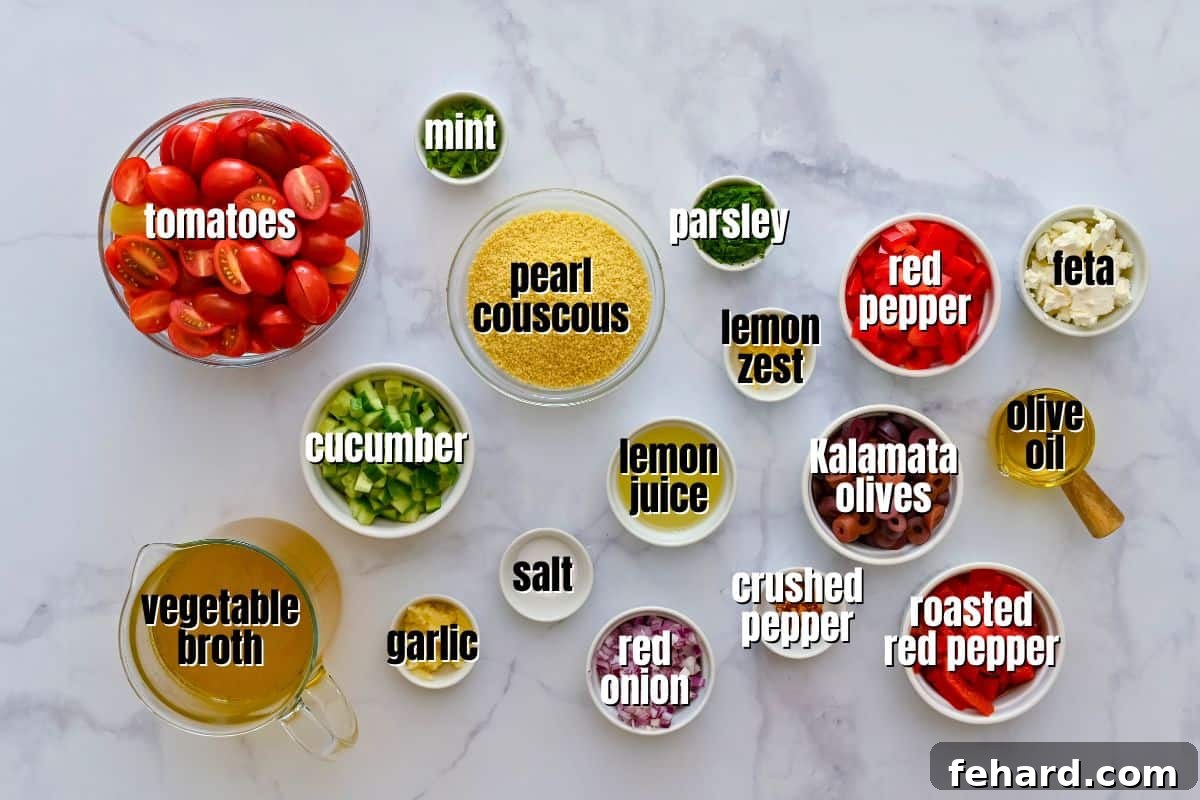 Array of fresh ingredients for couscous salad, neatly arranged on a kitchen counter: pearl couscous, vegetable broth, grape tomatoes, cucumber, olives, red peppers, onion, feta, and lemon dressing components.