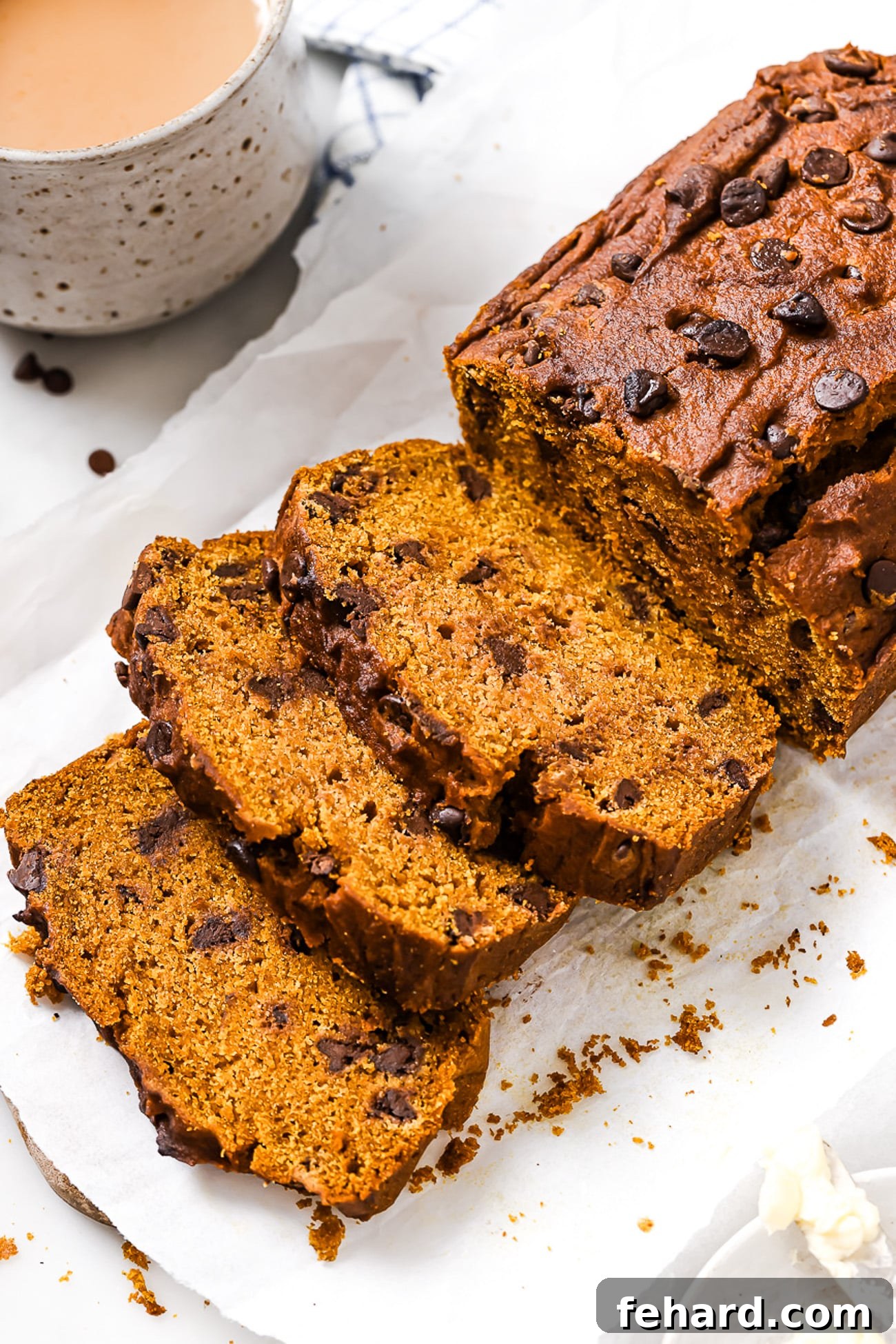 Cozy Autumn Pumpkin Chocolate Chip Loaf 10 Sliced pumpkin chocolate chip bread on parchment paper.