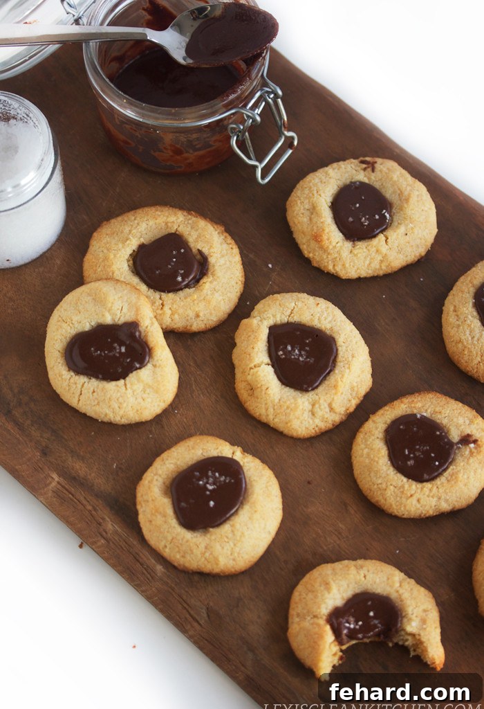 An overhead view of Sea Salt Nutella Thumbprint Cookies with homemade nutella in on the side. A paleo and healthier take on a beloved classic, with a hint of sea salt.