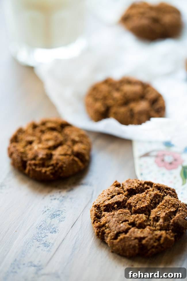 Four healthy ginger snaps arranged on a wooden tabletop. Classic spice and crunch in a healthier package.