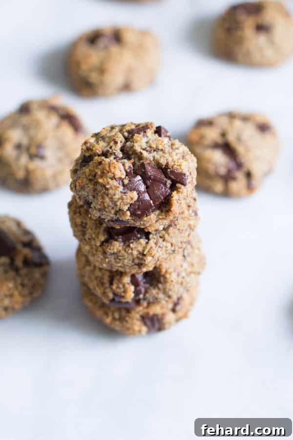 A stack of Chocolate Chunk Hazelnut Cookies with more cookies in the background. A sophisticated and nutty chocolate cookie for the holidays.