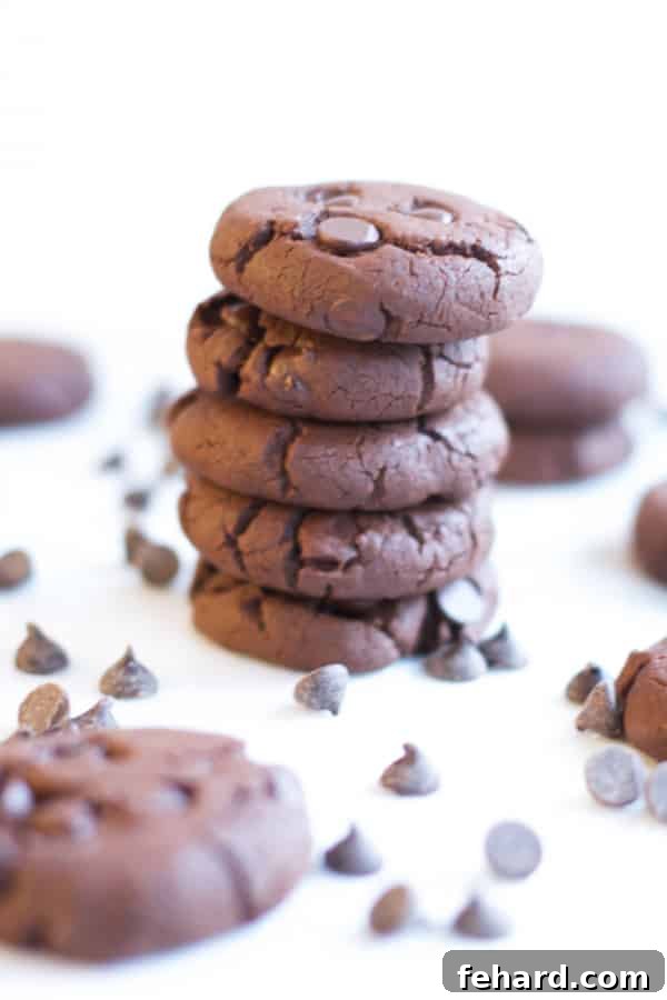 A stack of Gluten Free Chocolate Chunk Cookies with chocolate chips and more cookies in the background. A rich and satisfying chocolate cookie for gluten-free diets.