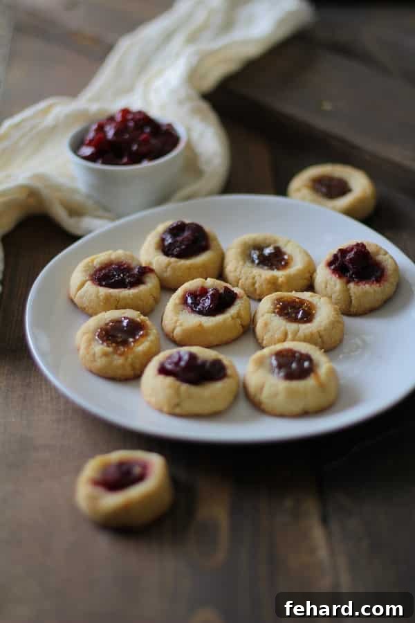 Several Cardamom Almond Paleo Thumbprint Cookies on a white serving plate. Delicately spiced and perfect for a paleo diet.
