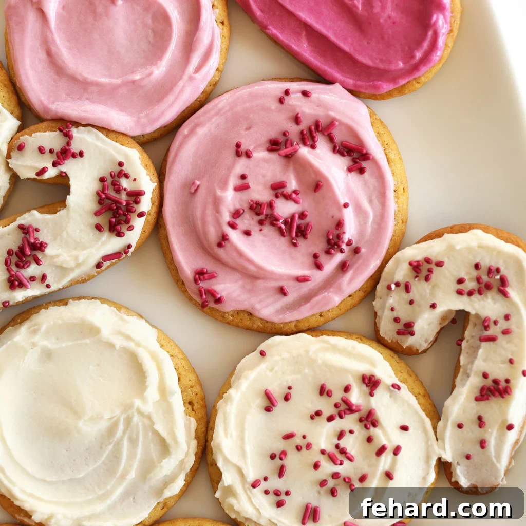 Vegan Sugar Cookies with white and pink frosting and red sprinkles. These festive cookies are entirely plant-based and ideal for decorating.