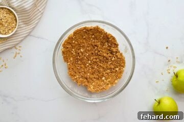 Apple crisp topping ingredients, including brown sugar and oats, being combined in a bowl.